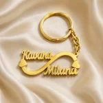 Double Name Infinity Keychain in gold brass on an ivory silk background