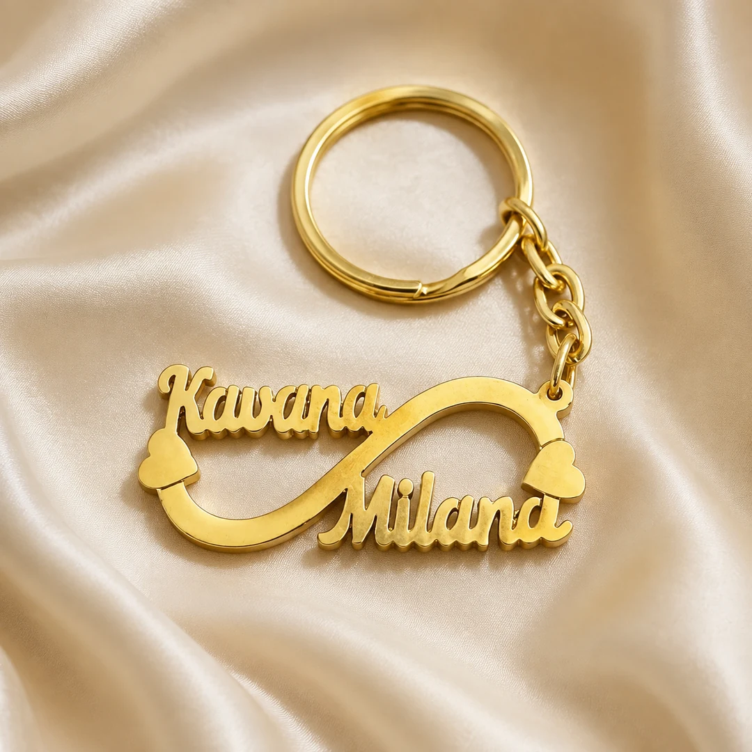 Double Name Infinity Keychain in gold brass on an ivory silk background