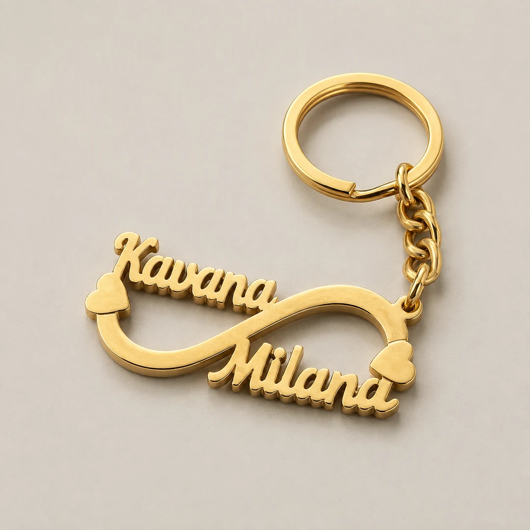 Double Name Infinity Keychain in gold brass on a warm gray studio background